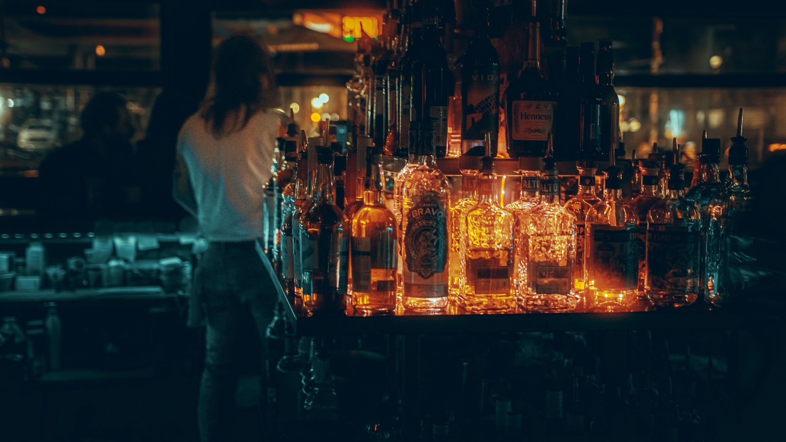 Warmly lit, well-stocked cocktail bar with liquor bottles